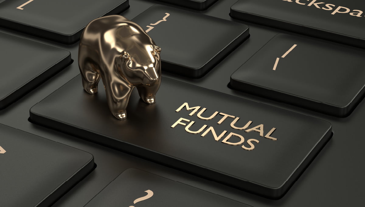 Mutual fund written in gold on a keyboard key with a golden bear toy standing on the button.