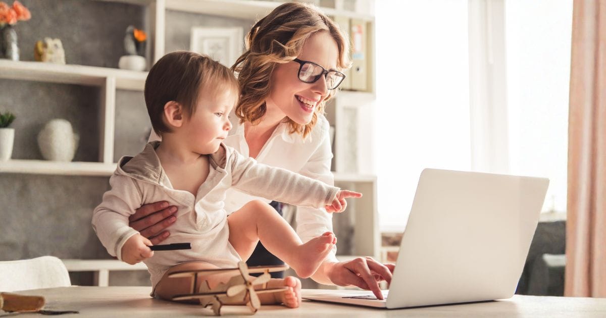 A successful woman working on a computer while caring for a toddler